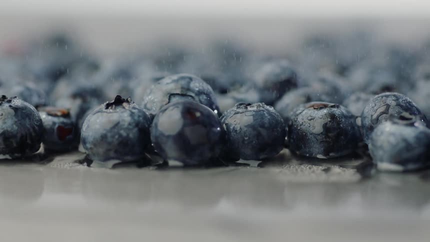 Blueberries bounce up on a surface covered in water