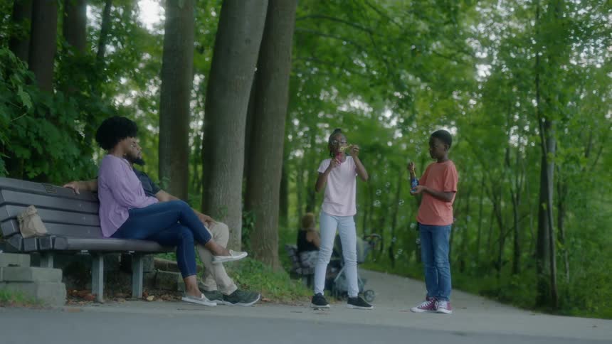 Kids are playing outside while parents are sitting on bench