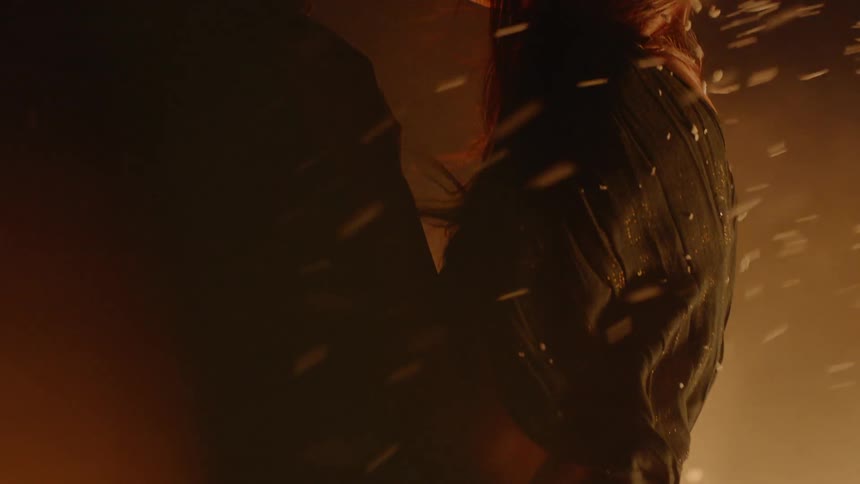 Man hugs a woman while they stand outside by fire and smoke