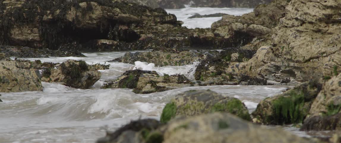 Water splashing on moss covered boulders and rocks