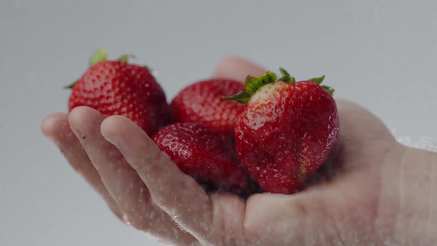 A hand holding strawberries