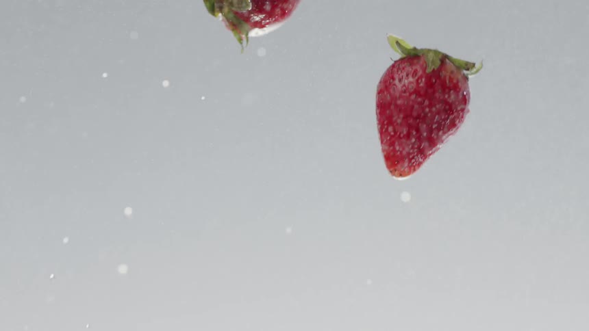 A handful of strawberries being thrown in the air