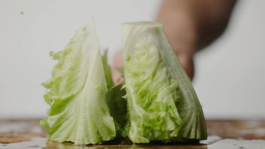 Lettuce is chopped on a wet cutting board