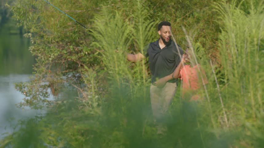A father and son fishing in a river at a park