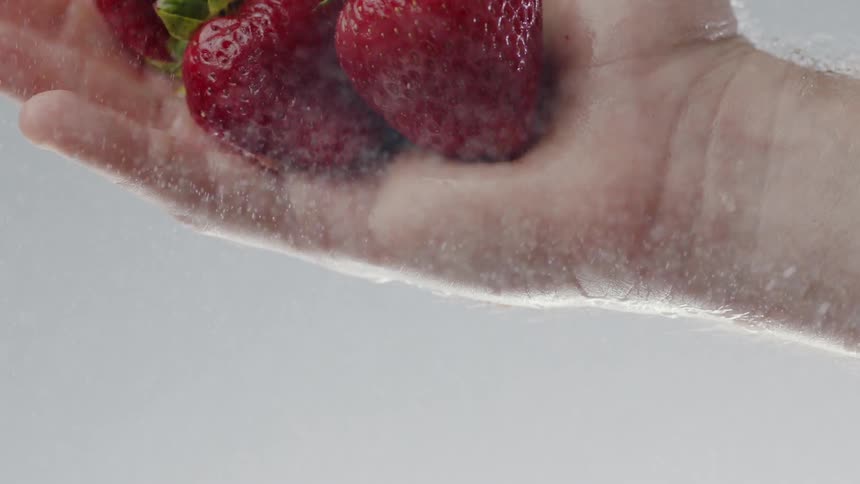 A man drops a handful of red strawberries