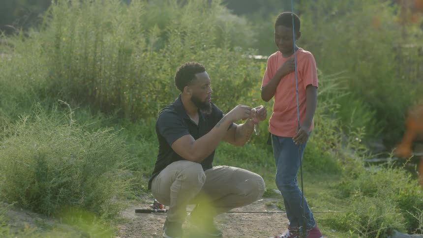 A father showing his son how to put bait on a fishing pole