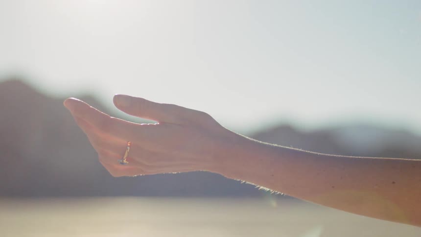 Woman wearing dress is raising her arm outside
