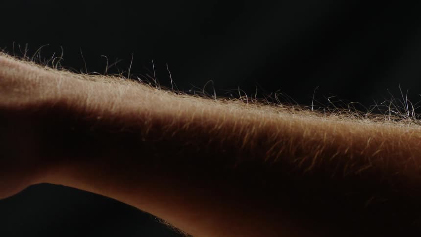 A balloon and static electricity cause the hair on a man's arm to stand up