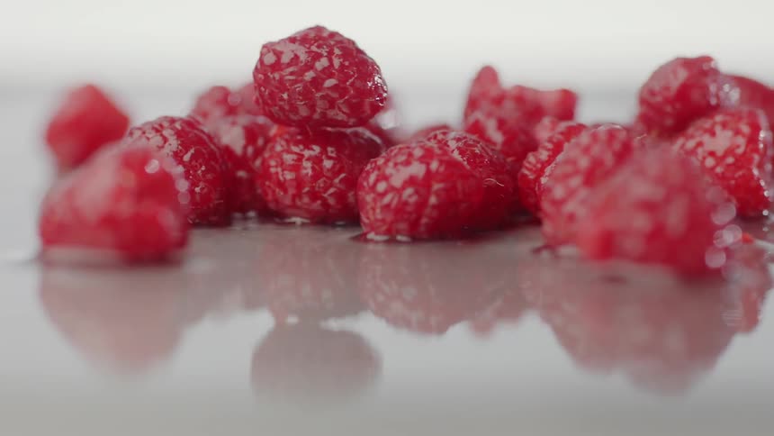Raspberries falling on a wet table