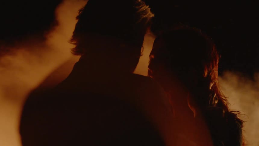 Man and woman hug outside by fire and smoke