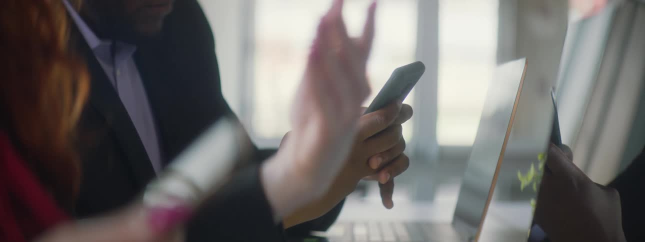 Man sitting at desk next to woman handles cell phone