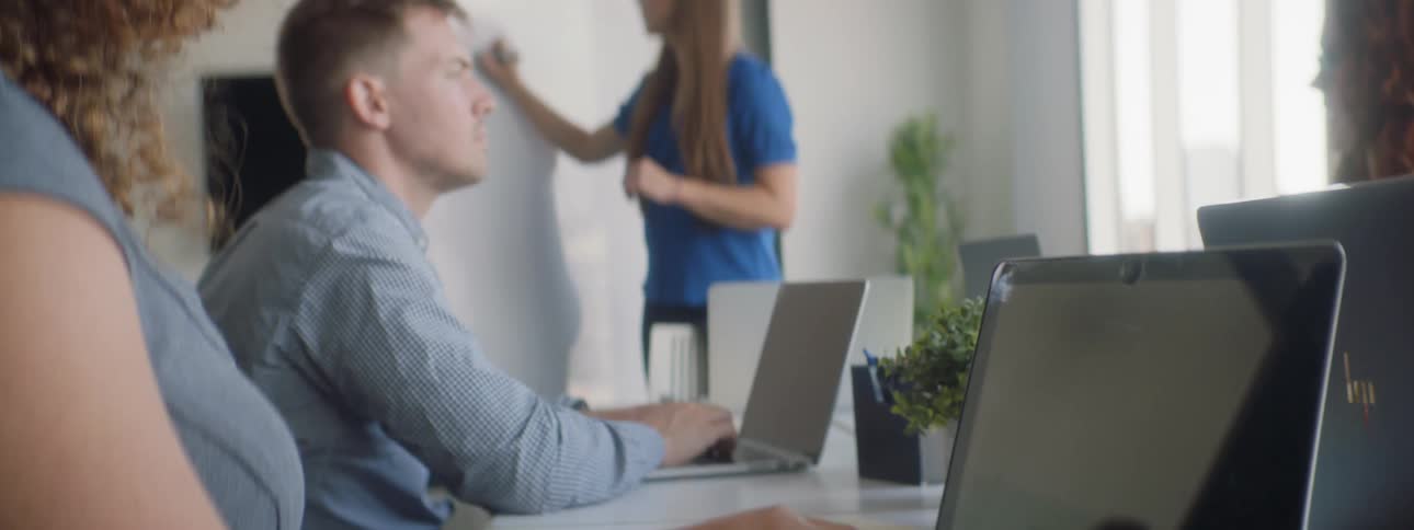 Man and woman type while another woman writes on whiteboard in office