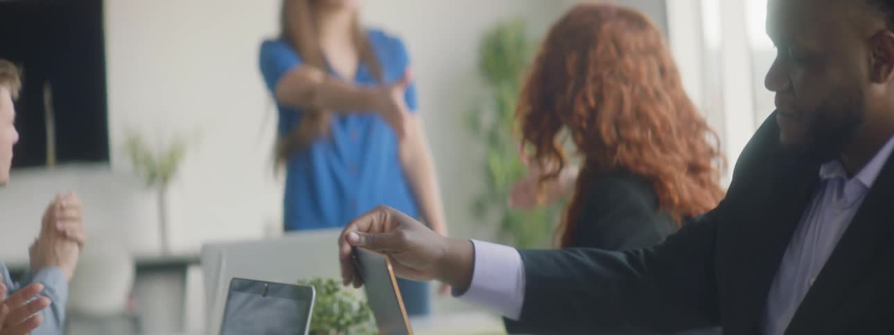 Coworkers applaud and shake hands at the end of a work meeting