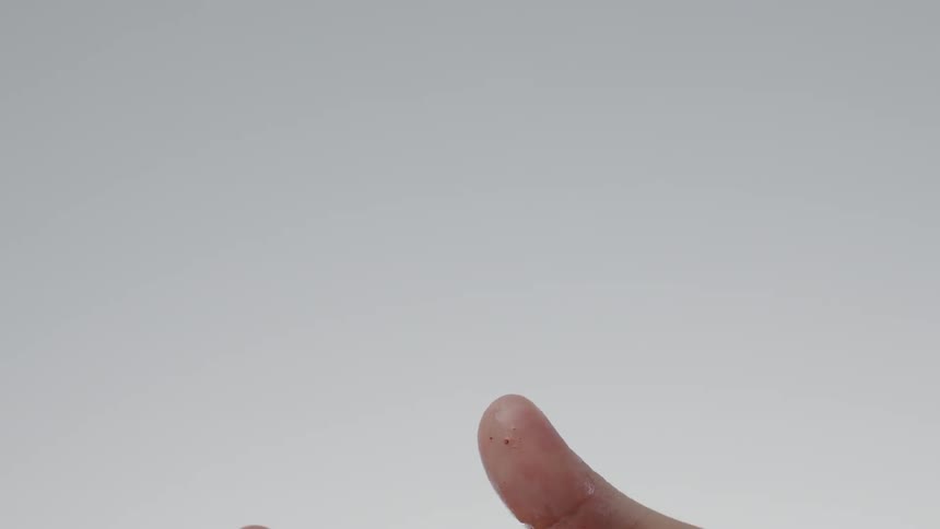 A hand tosses and catches a wet strawberry