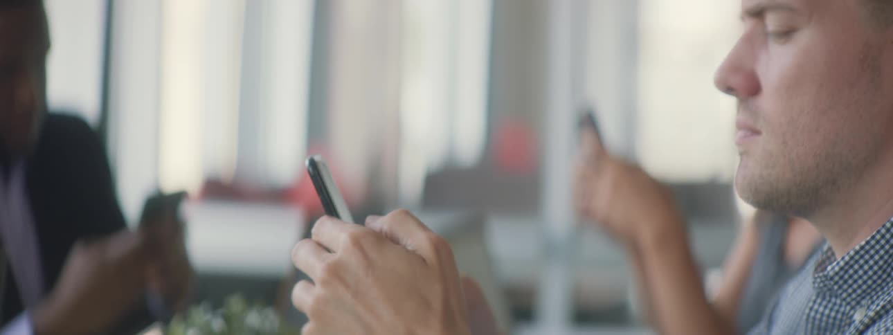 People sit at a table all using their phones