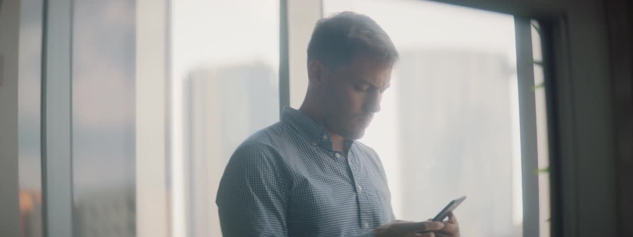 A man uses a phone next to a window