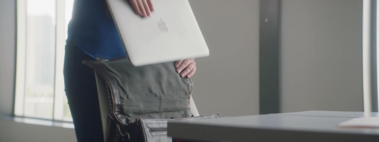 A woman is opening a briefcase and taking a laptop out