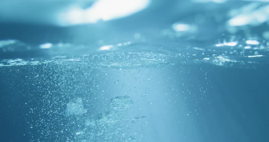 Bubbles rise to the surface of the water, towards the light
