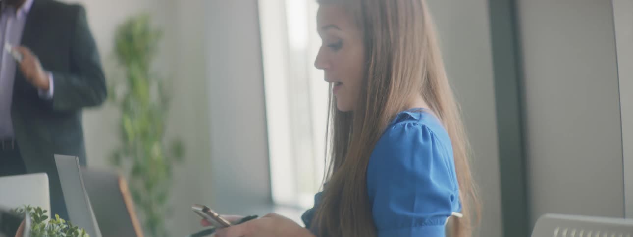 A woman sitting in a meeting and looking at her phone