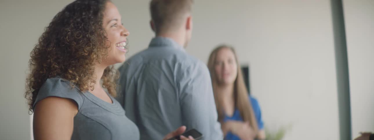 Man and woman smile and shake hands in a conference room