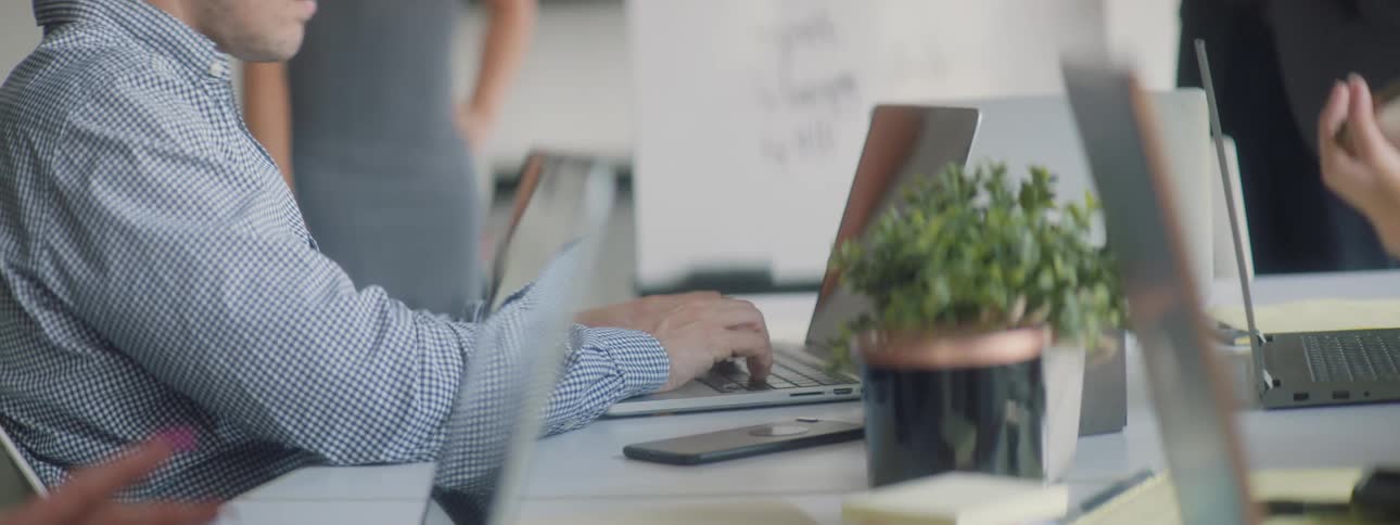 Man is sitting and typing on laptop in company meeting