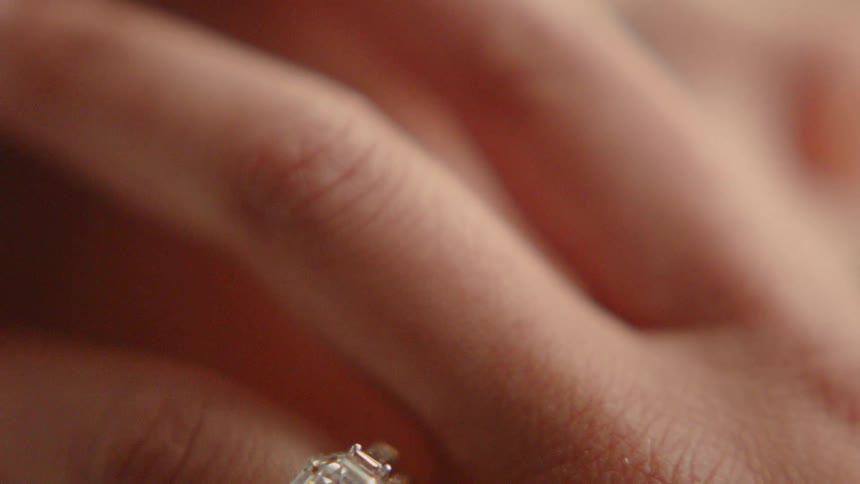 A woman's hand with a diamond ring that is touching a baby's face