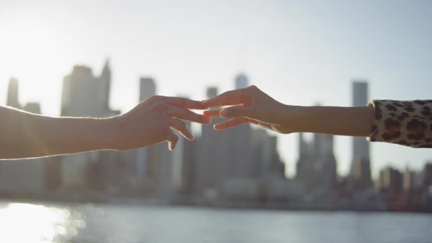 Two hands holding each other in front of New York City