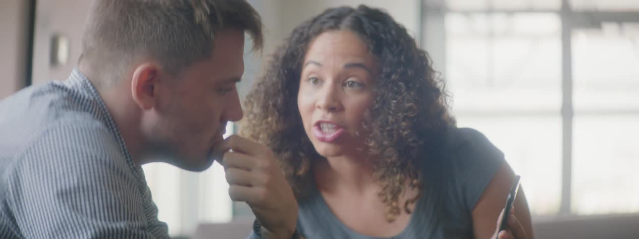 A woman is talking to a man and holding a cellphone