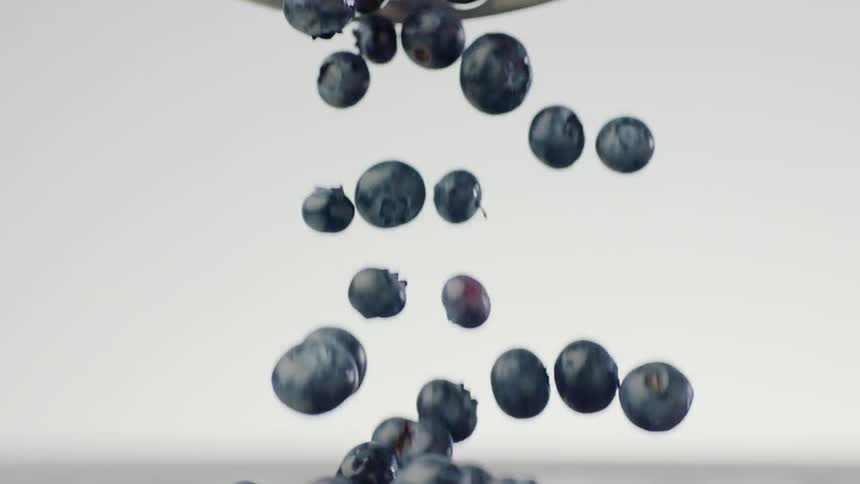 A bowl of blueberries is poured onto a wet table