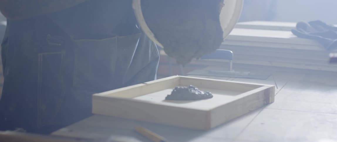 Someone dropping cement from a bucket to a wooden frame