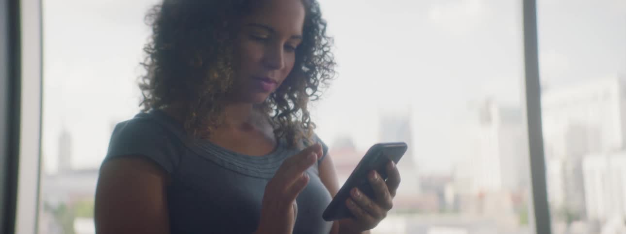 A woman in an office scrolling on her phone
