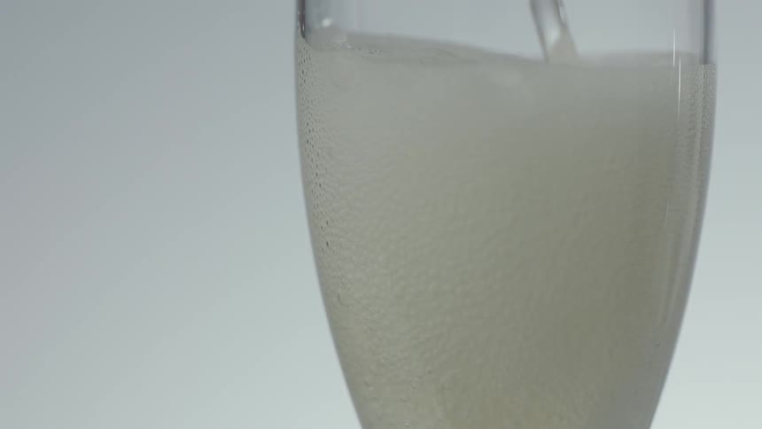 Clear bubbling liquid splashes into a champagne glass
