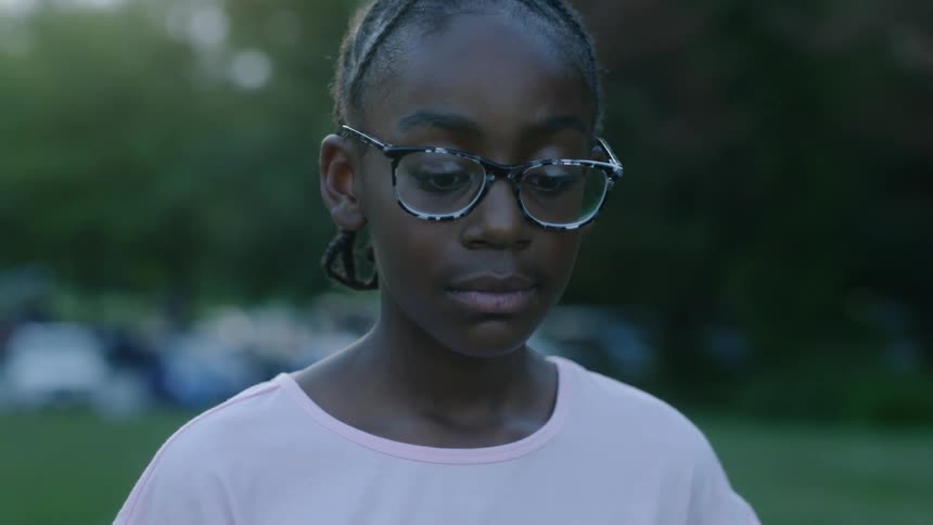 A girl in glasses and a pink shirt staring at something off screen