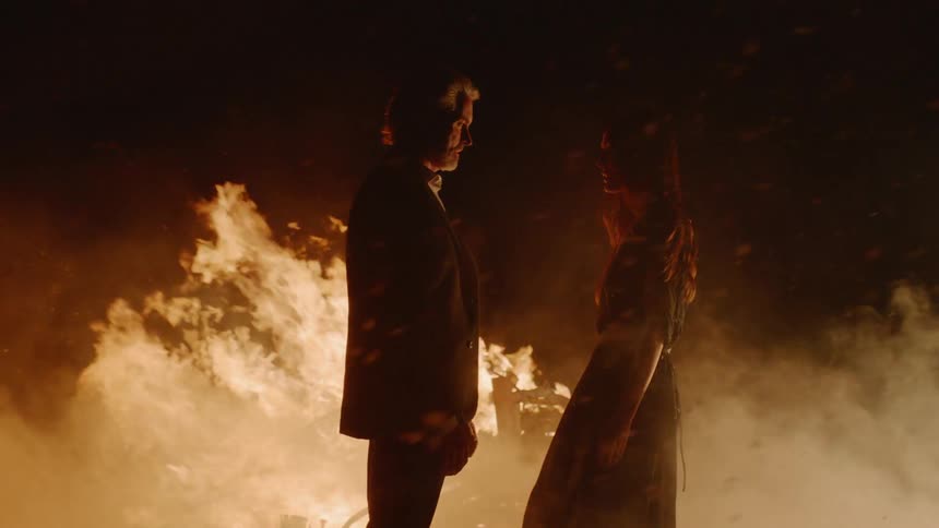 Man and woman are embracing and kissing next to bonfire at night