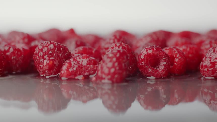 Raspberries bounce on a surface covered in water