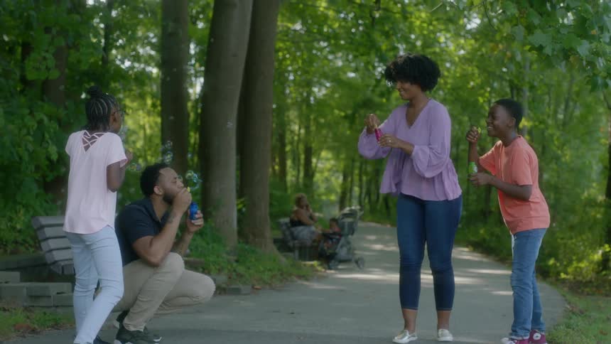 Family blows bubbles on trail in forest