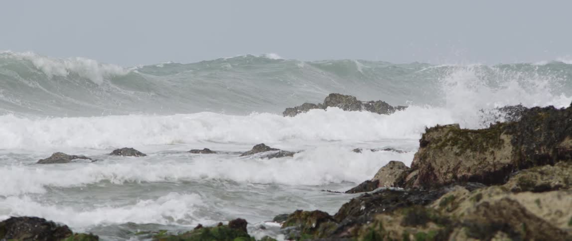 Many waves crashing onto the rocky coastline
