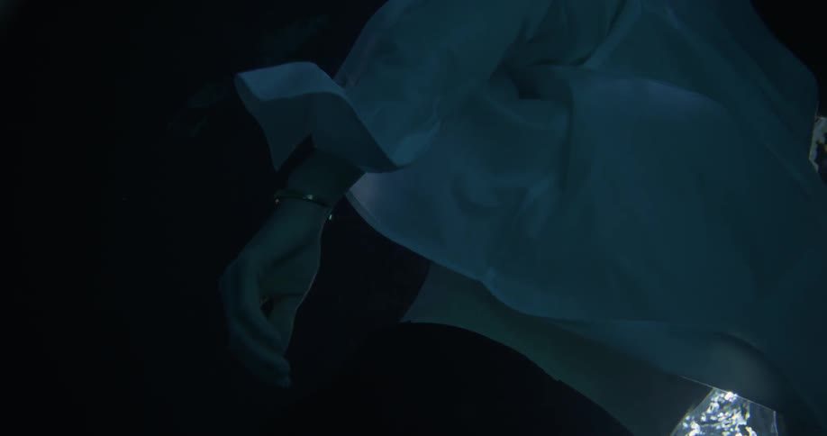 A woman with a white blouse drifts lazily through water
