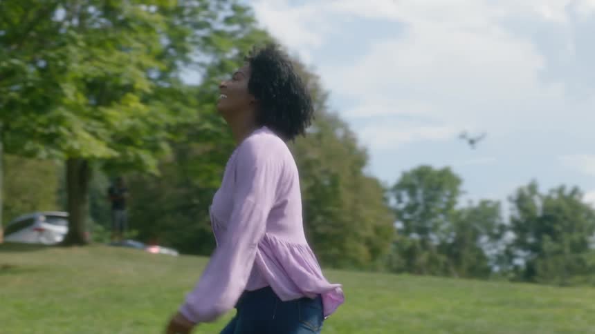 Woman smiles and runs in the park on a sunny day