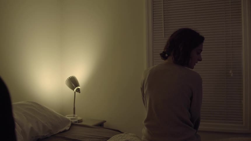 Woman sits on the edge of a bed at night