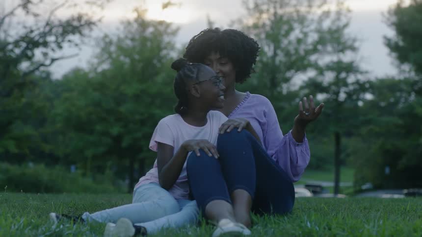 A mother and daughter sit together in the grass