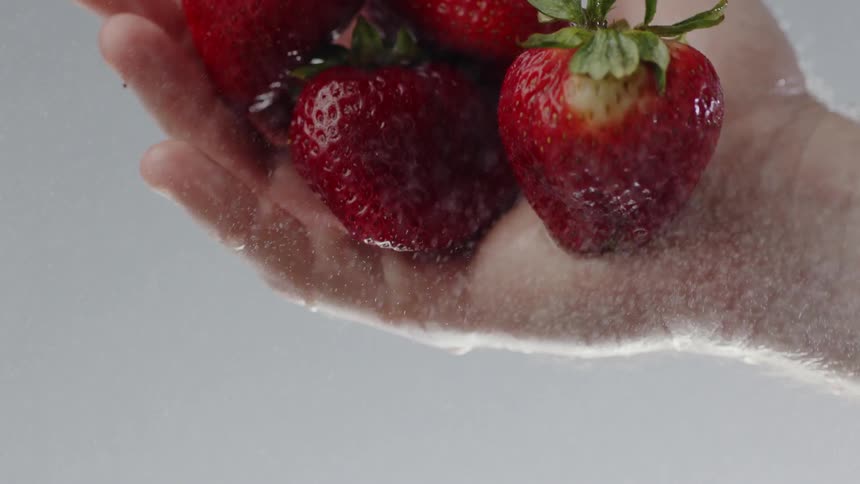 A hand flipping and dropping strawberries