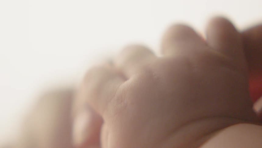 A baby grasps an adult's finger