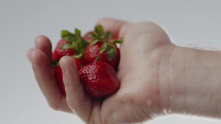 A handful of strawberries being held by a man