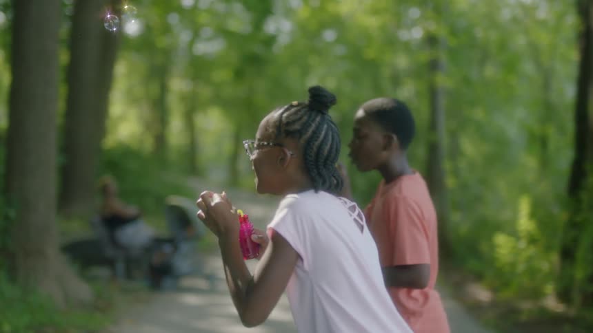 Children play outside in nature with bubbles