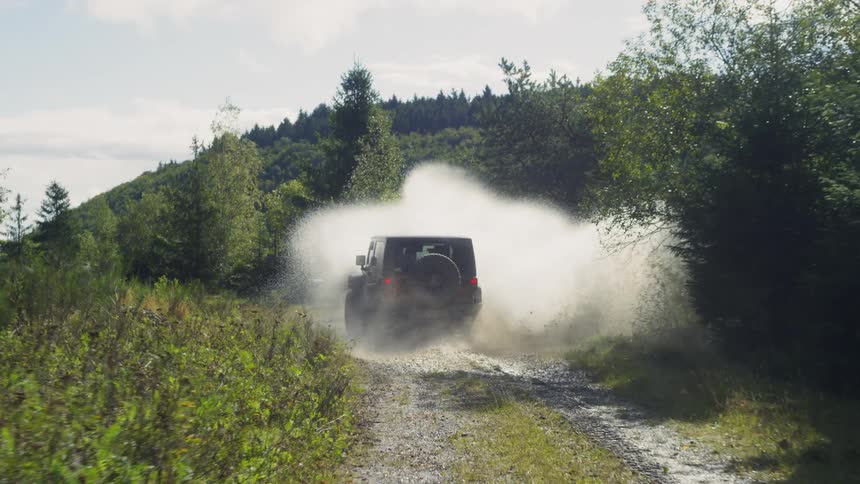 An all-terrain vehicle on a dirt road driving through a puddle