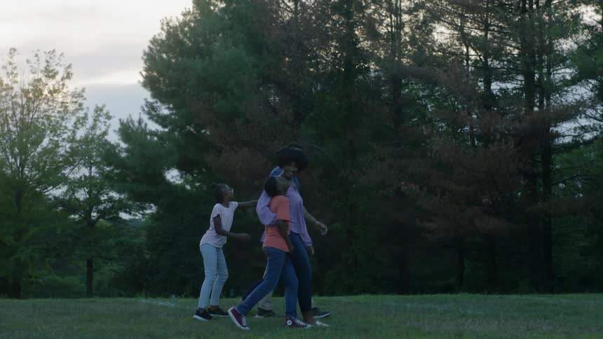 A family hug and walk together on the grass