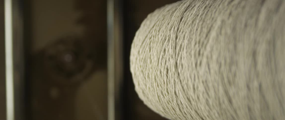A machine unwinds thread from a large spool