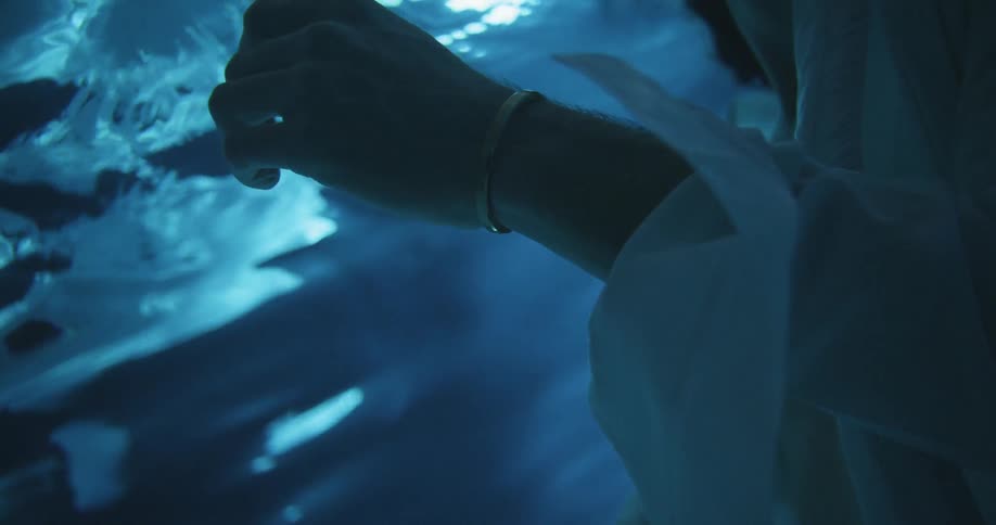 Person floats underwater and their hand touches the surface