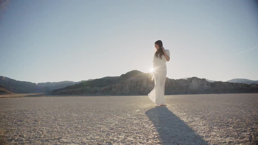A woman on the salt flats turns away from the wind